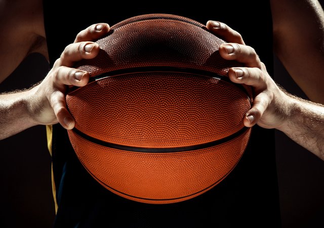 silhouette_view_of_a_basketball_player_holding_basket_ball_on_black_wall