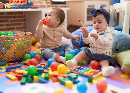 two_toddlers_playing_with_balls_xylophone_sitting_floor_kindergarten
