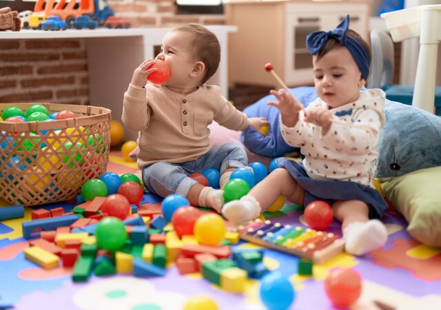 two_toddlers_playing_with_balls_xylophone_sitting_floor_kindergarten